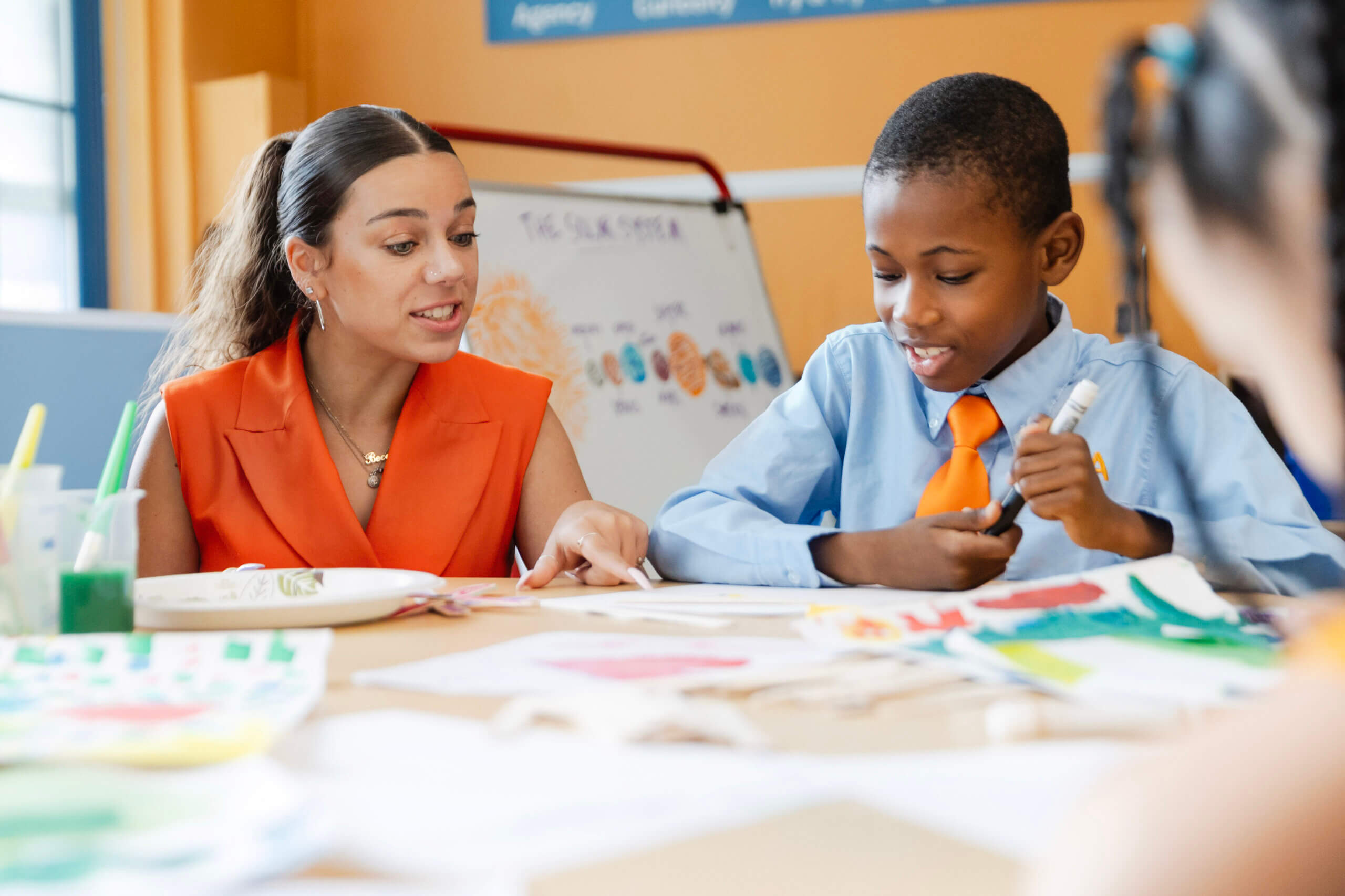 teacher working with a student sitting at a desk