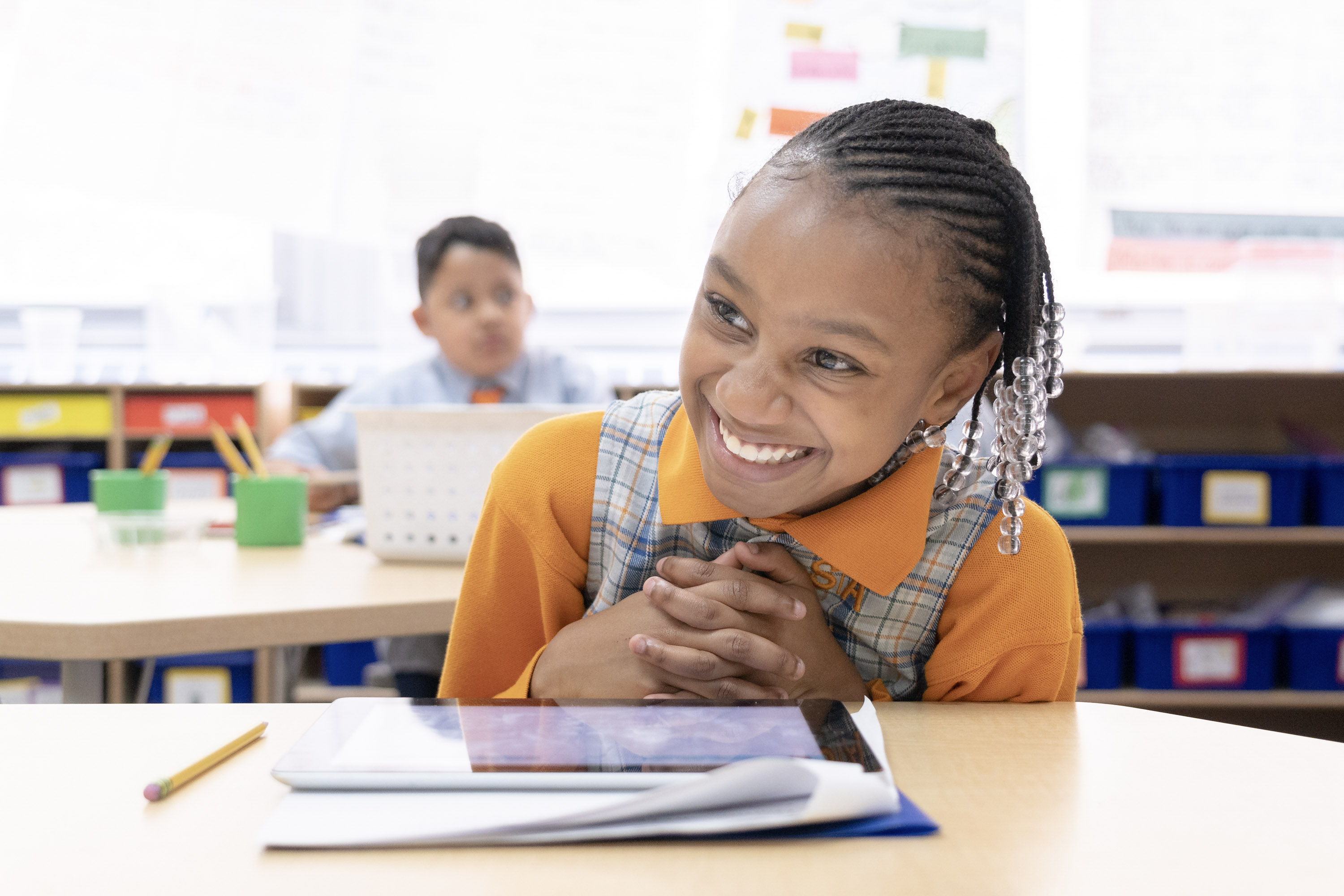 smiling student sitting at a desk with interlocked fingers