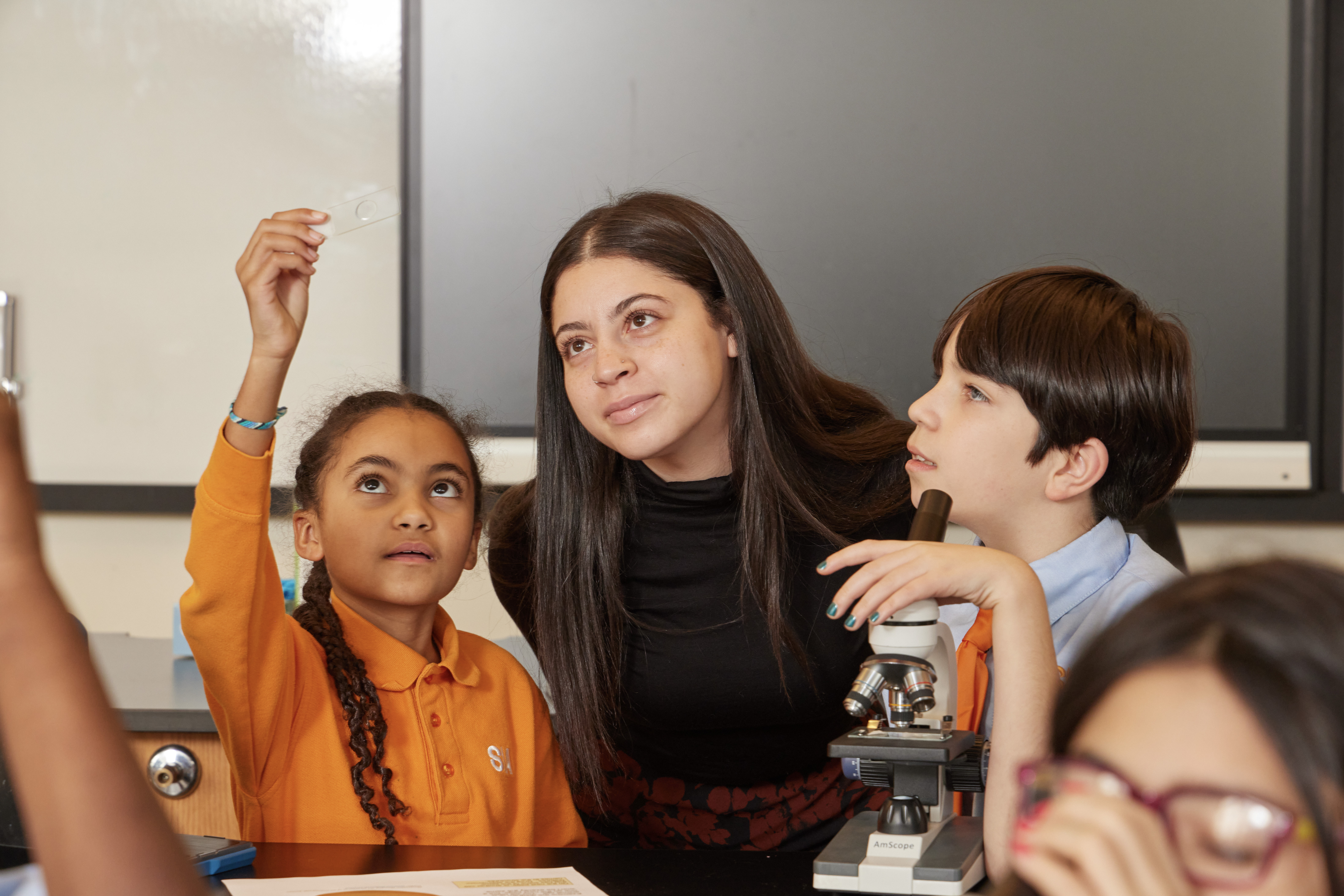 students looking at microscope slide with teacher