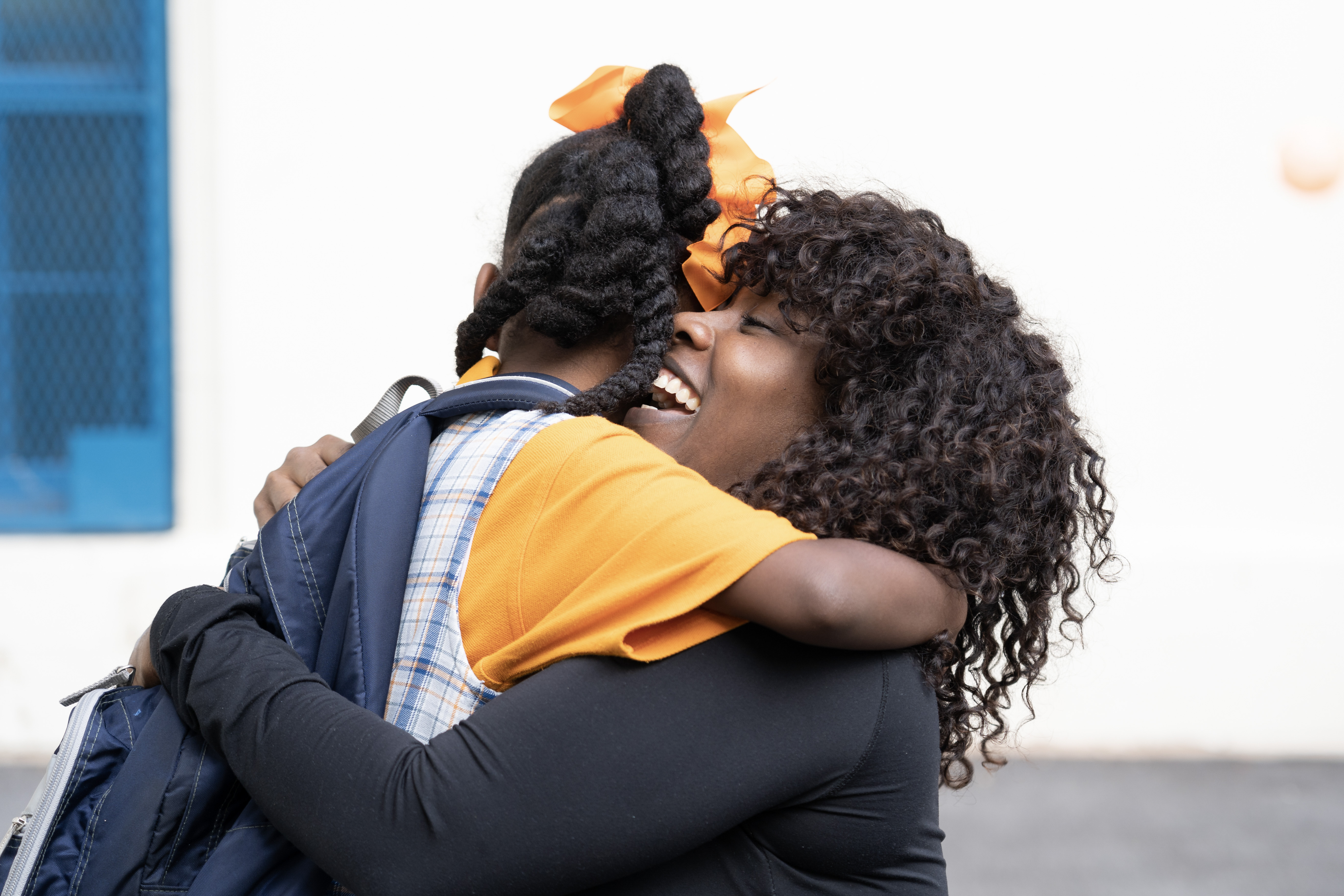 A mother and child hugging outside of a school