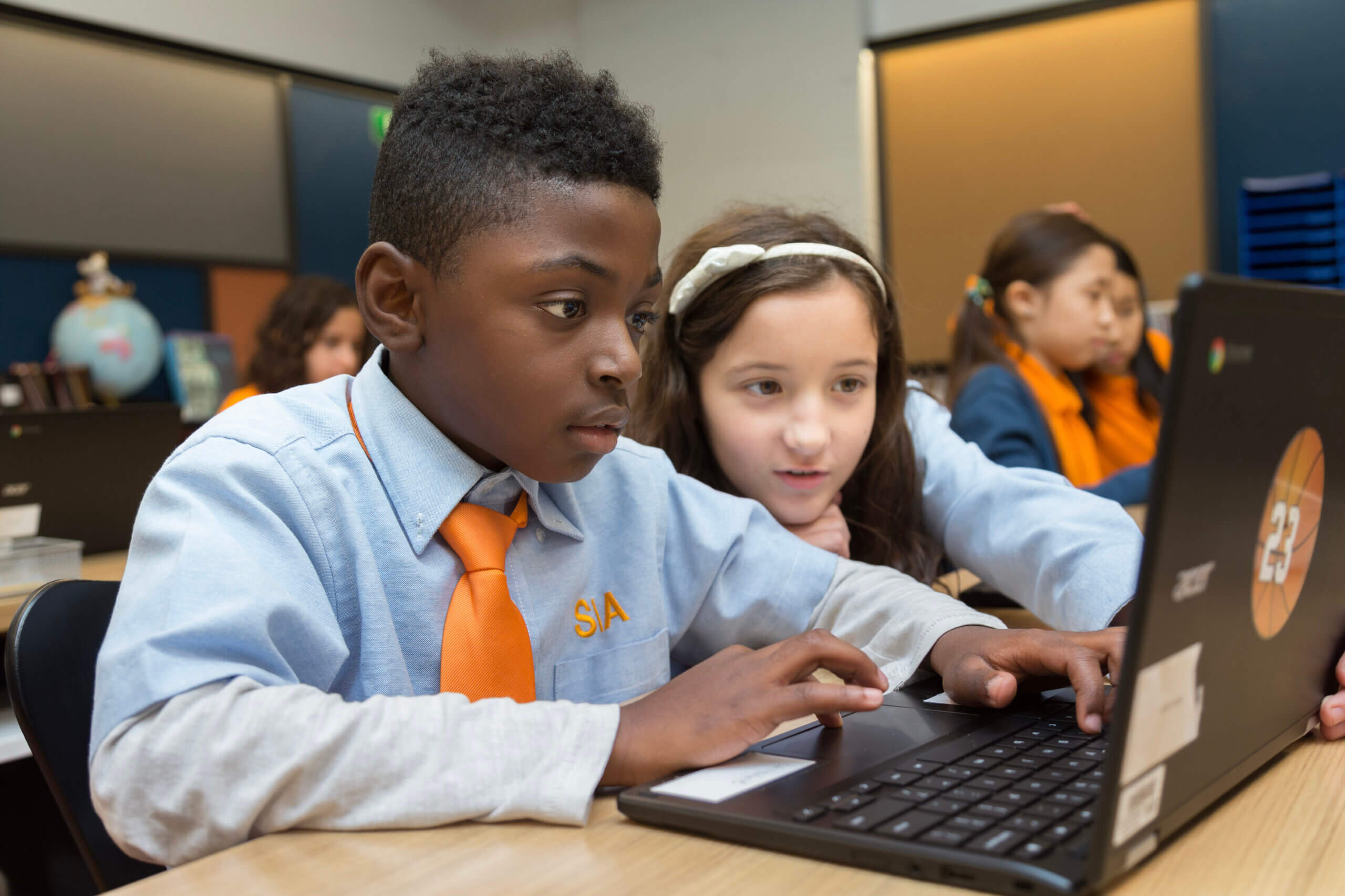 Two children in Success Academy uniforms looking at a laptop